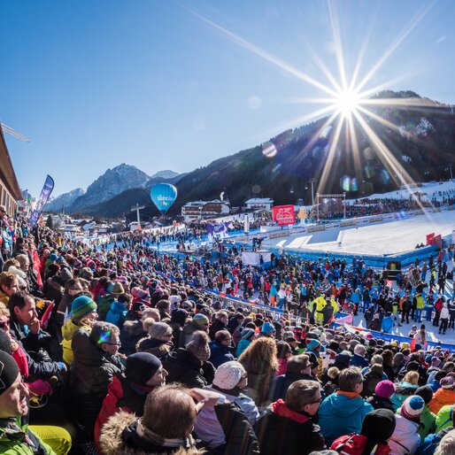Der Zielbereich eines Skirennens mit zahlreichen Besuchern und der Sonne und den Bergen im Hintergrund. | © Harald Wisthaler