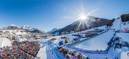 Der Zielbereich eines Skirennens mit den Zuschauerrängen und dem strahlend blauen Himmel und Bergpanorama im Hintergrund. | © Harald Wisthaler