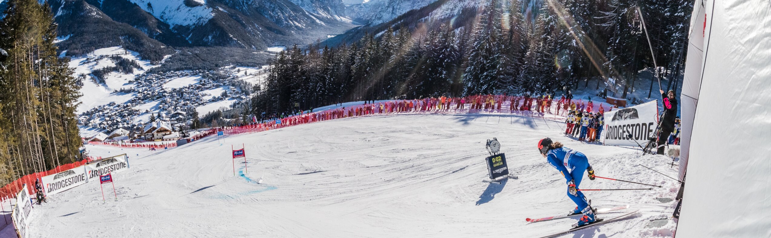 Eine Skirennläuferin beim Start auf der Erta Piste mit Aussicht auf die Dolomiten bei strahlendem Sonnenschein. | © Harald Wisthaler