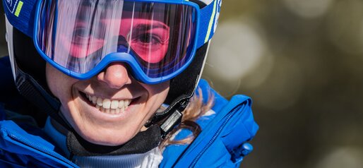 Porträt einer Skifahrerin mit weißem Skihelm, blauer Skibrille und blauer Skijacke. | © Harald Wisthaler