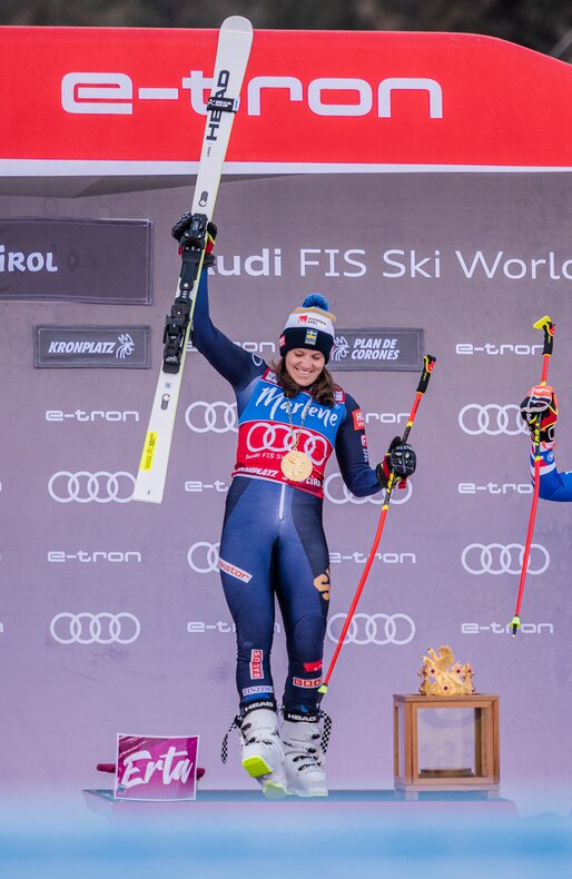 Drei Skirennläuferinnen stehen jubelnd auf dem Podest und halten ihre Skier in die Höhe. | © Harald Wisthaler
