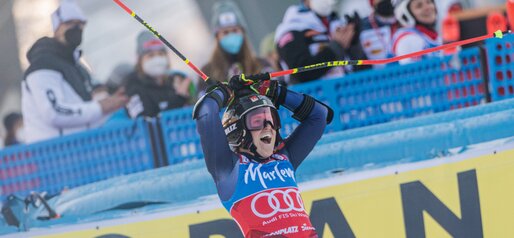 Eine Skirennläuferin hält nach dem Rennen überrascht die Skistöcke in die Höhe, im Hintergrund jubeln Teammitglieder. | © Harald Wisthaler