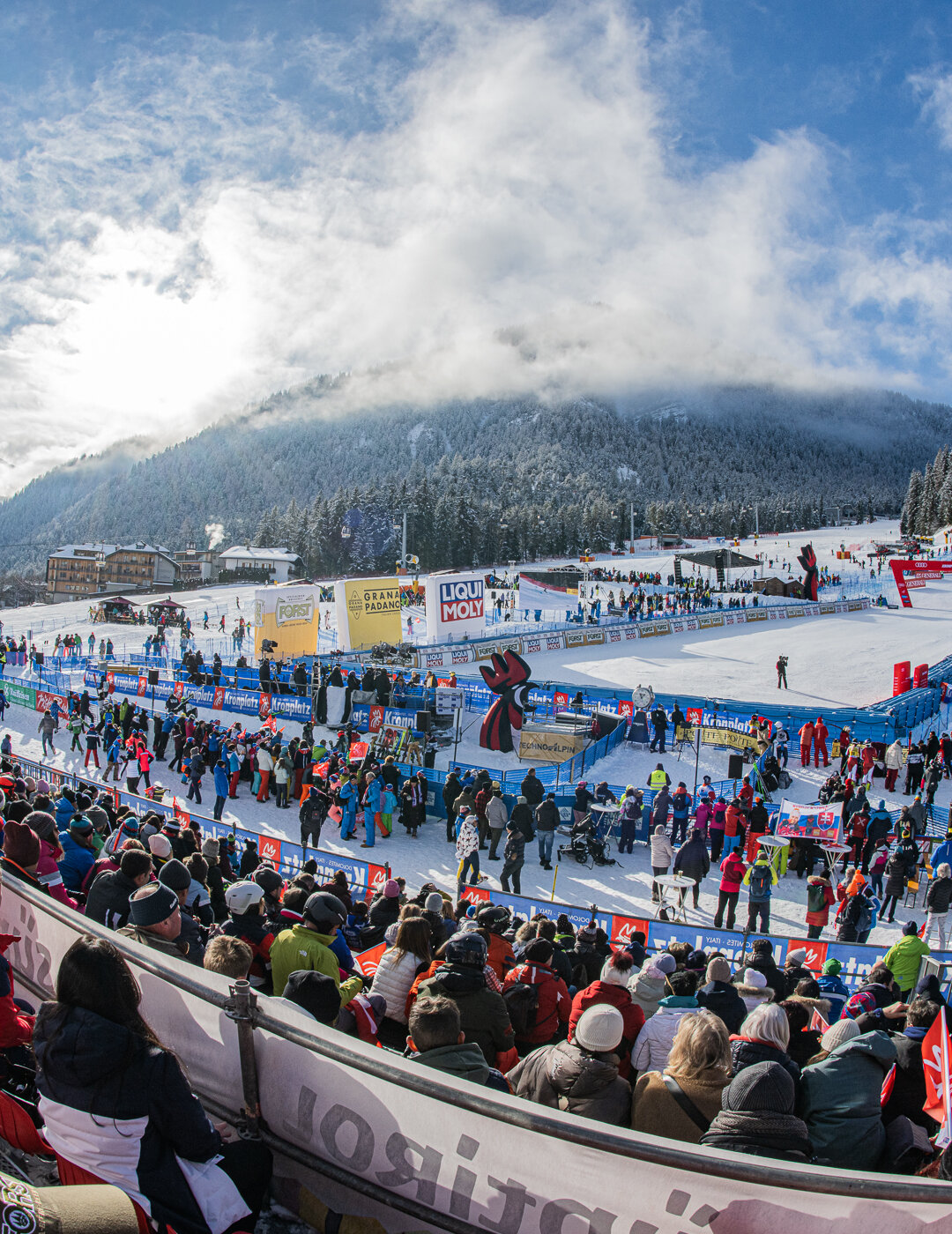 Das Foto zeigt die Tribüne voller Zuschauer und den Zielbereich  der Erta Piste bei blauem Himmel und vereinzelten Wolken. | © Harald Wisthaler