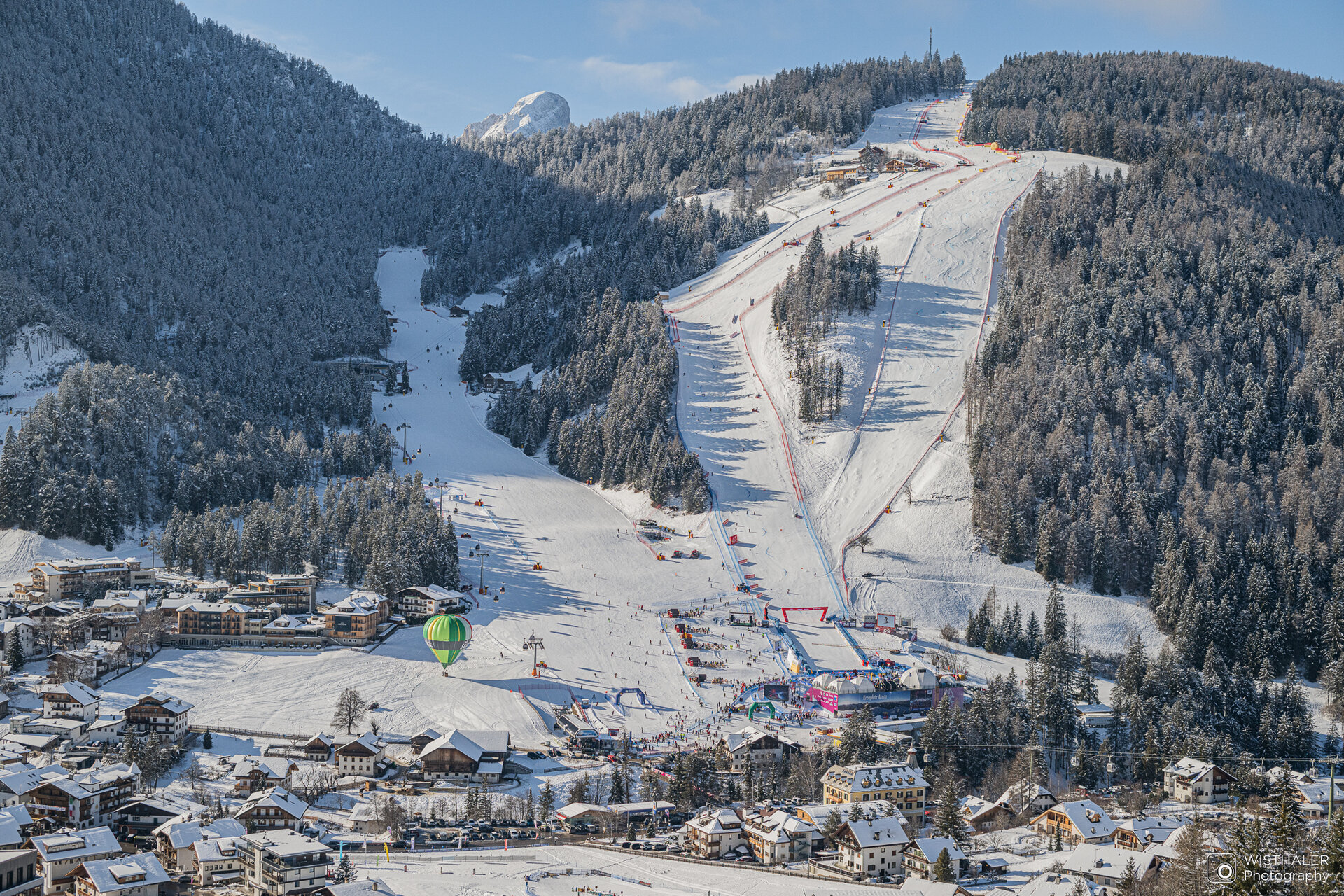 Die Skirennstrecke Erta mit einigen Häusern im Vordergrund und Wald und blauem Himmel im Hintergrund. | © Harald Wisthaler