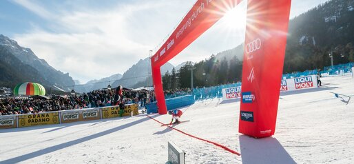 Eine Rennläuferin kommt in den Zielbereich, im Hintergrund strahlendes Wetter und jubelnde Zuschauer. | © Mattia Negrini