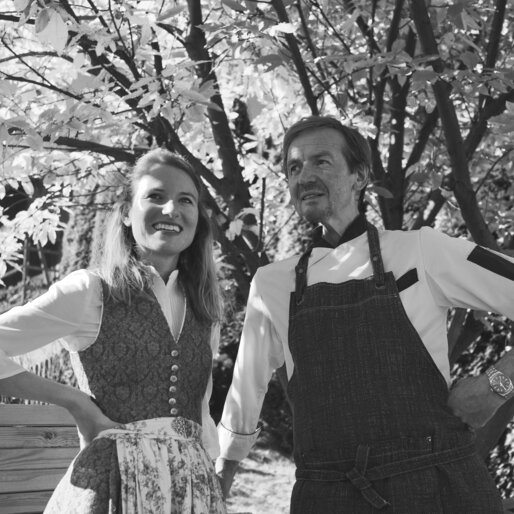 Ein Koch und eine Frau im Dirndl im Garten.