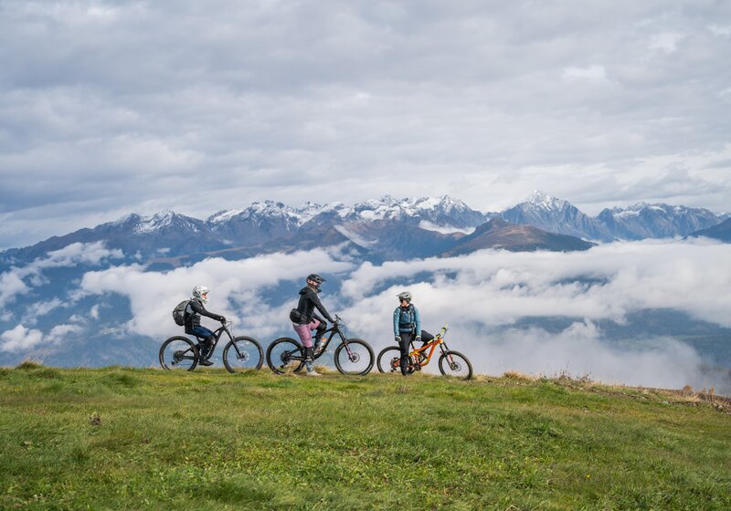 Drei Fahrradfahrer bei herbstlichen Temperaturen mit vernebelten Bergen im Hintergrund. | © Gianvito Coco