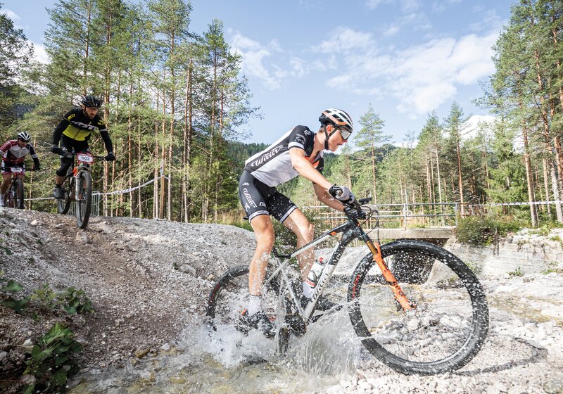Ein Teilnehmer des Kronplatz King Radrennes beim Durchqueren eines Flusses. | © Armin Huber