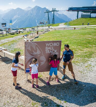 Eltern mit ihren beiden Töchtern bei der Holzkugelbahn am Kronplatz-Gipfel im Sommer. | © Harald Wisthaler