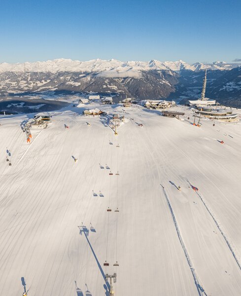 Weitläufige Skipisten mit Spuren im Schnee und umliegenden Bergen bei Tageslicht. | © Harald Wisthaler
