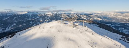 Panoramaaufnahme eines sonnigen Skibergs mit Blick über das Tal und umliegende Berglandschaft. | © Harald Wisthaler