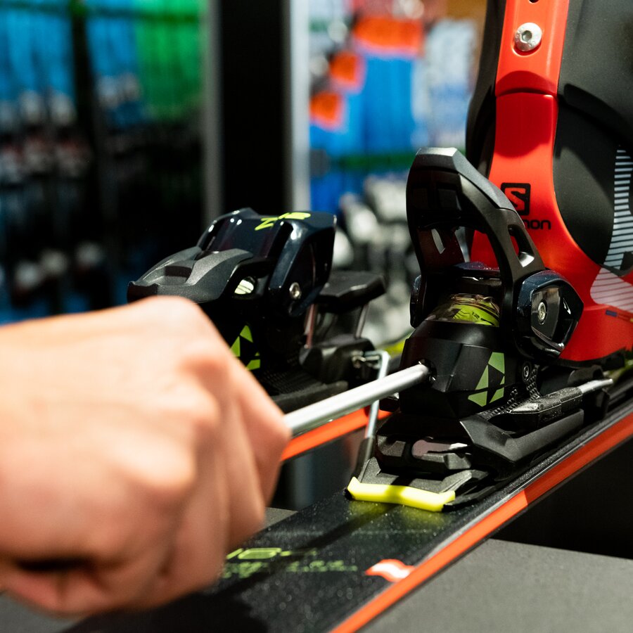 Ein Mitarbeiter des Skiverleihes passt den Skischuh an den Ski an. | © Skiarea Miara