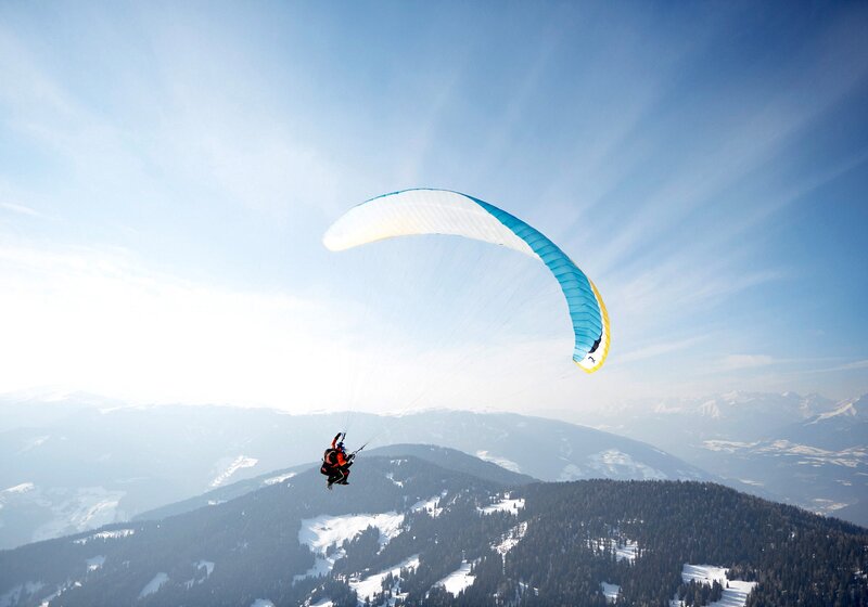 Ein Paragleiter im Winter oberhalb des Kronplatz-Gipfels. | © Tandemflights Kronplatz